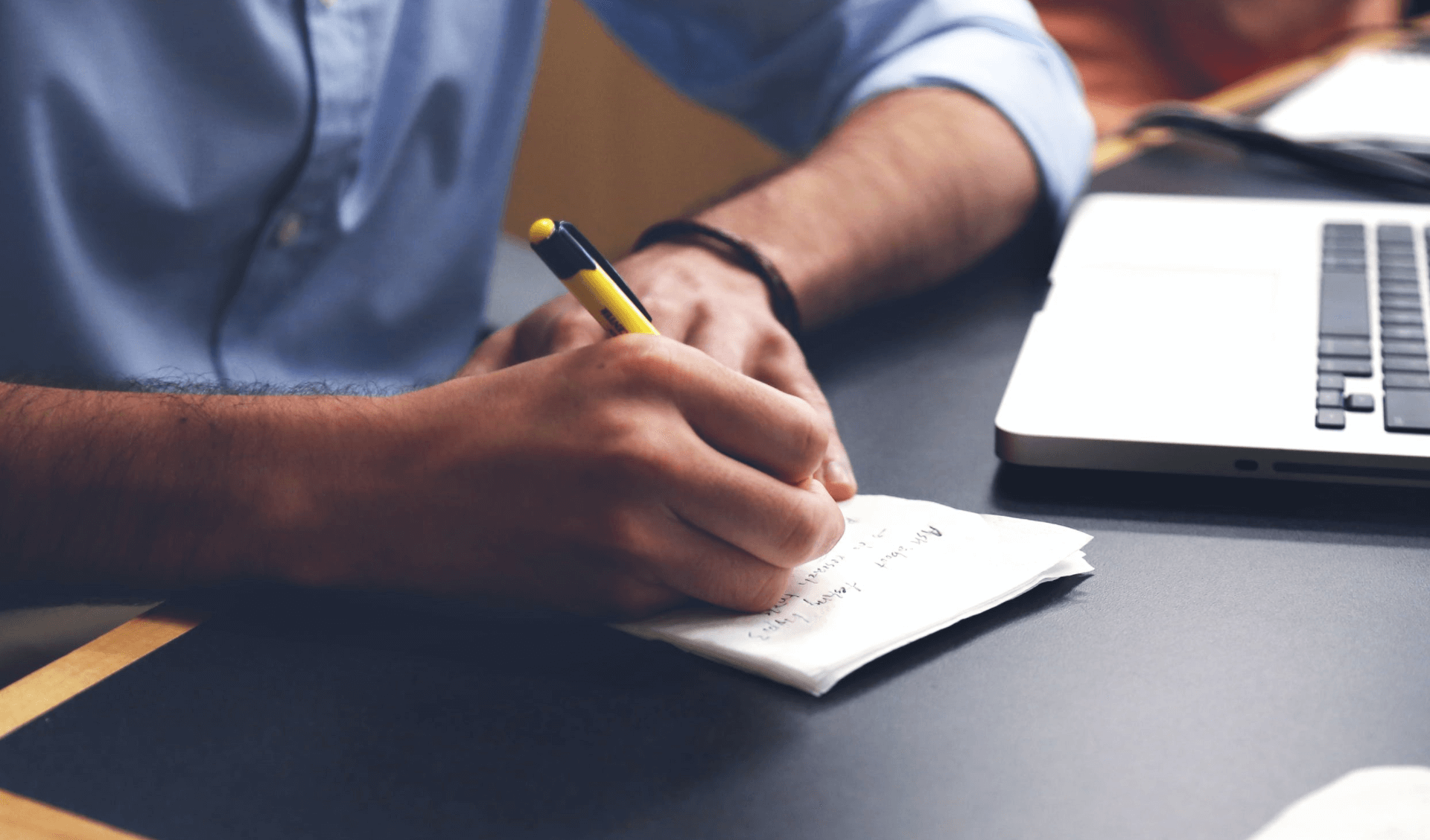 a photo of a person writing something down on a piece of paper