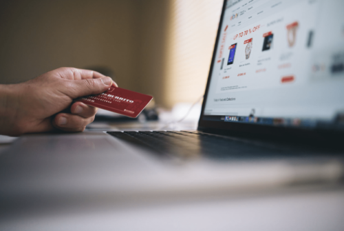 A photo of a person looking for a laptop screen with credit card in hand